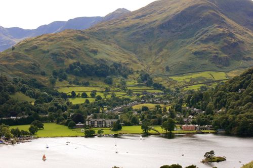 Free Scenic aerial view of a serene lake surrounded by lush green countryside and hills. Stock Photo