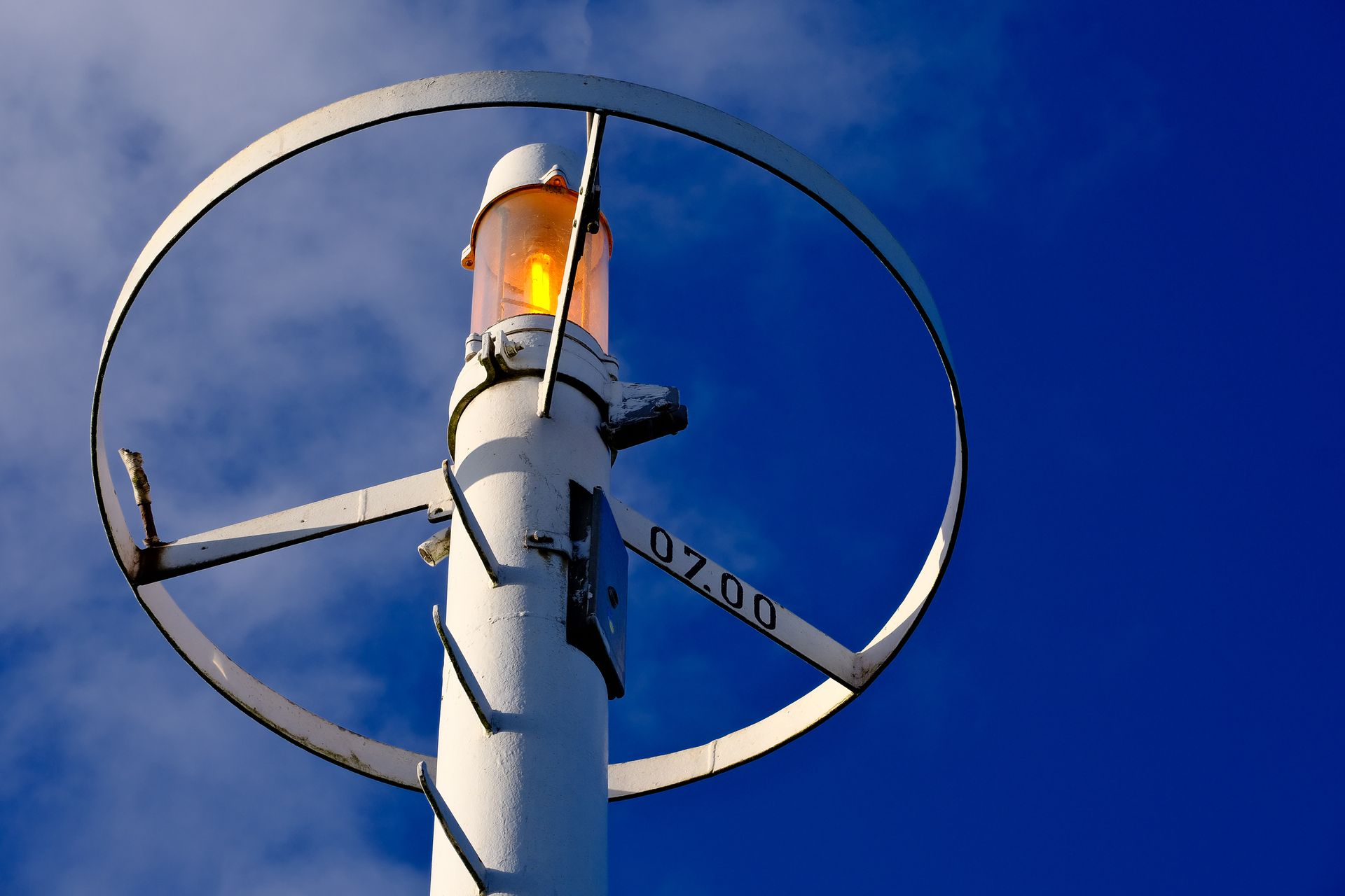 A close-up view of a lit signal tower against a vibrant blue sky, highlighting industrial design.