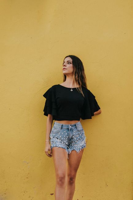 A fashionable woman posing against a vibrant yellow wall in Santiago de Querétaro, México.