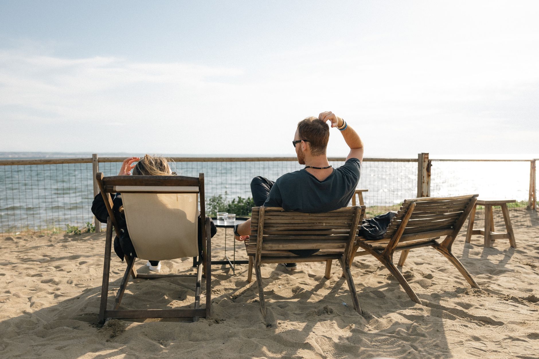 A couple sitting on chairs enjoying the peaceful seaside on a sunny day.