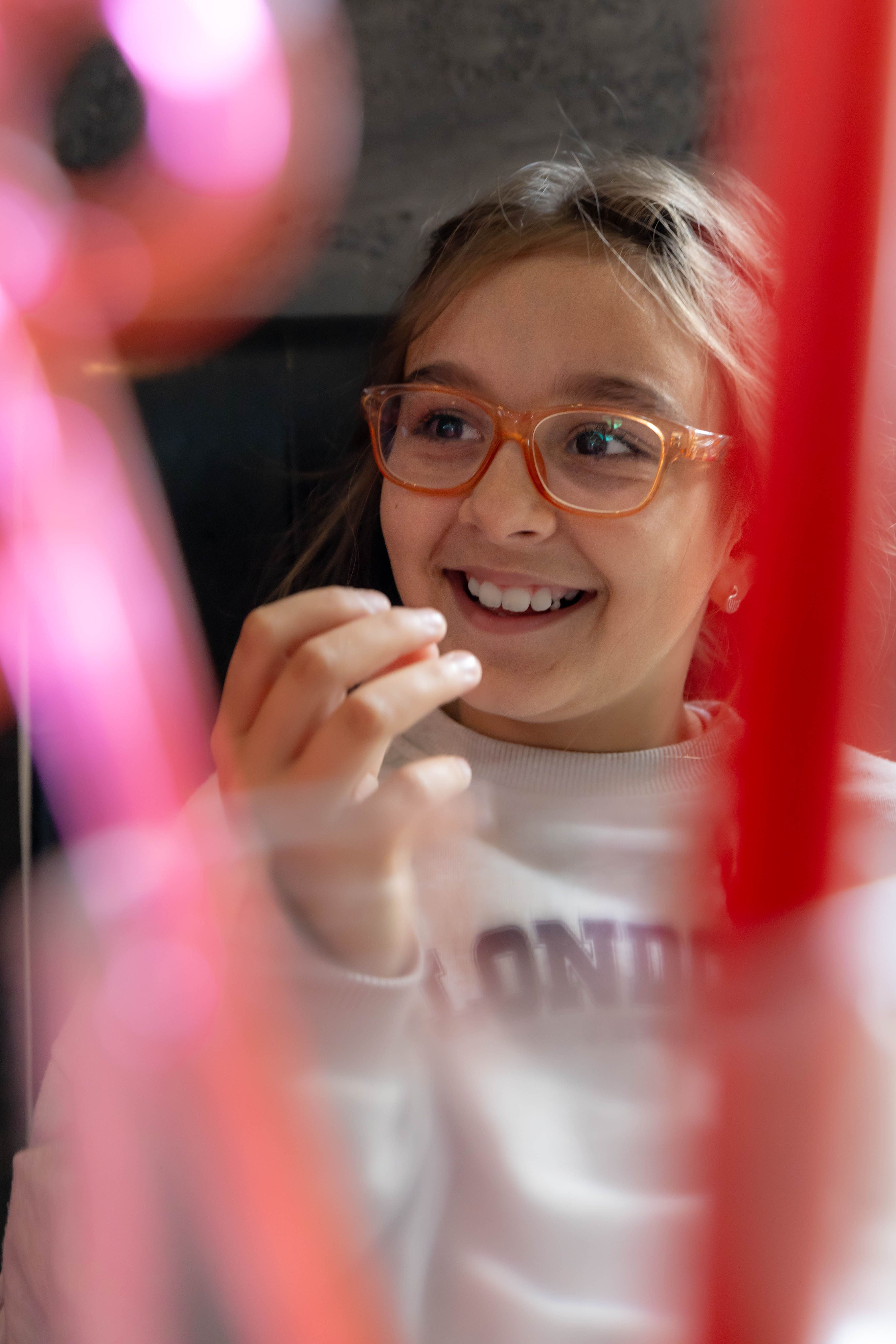 A cheerful child with glasses, smiling indoors, showcasing joy and innocence.