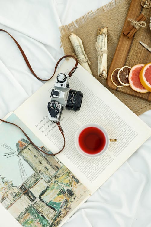 A book, camera and tea on a bed