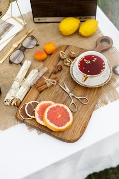 A rustic flat lay of tea, grapefruit, and accessories on a wooden board, creating a cozy breakfast setting.