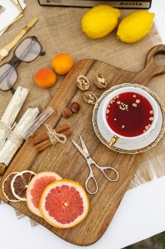 Flat lay of a wooden board with tea, citrus fruits, and nuts for a cozy rustic vibe.