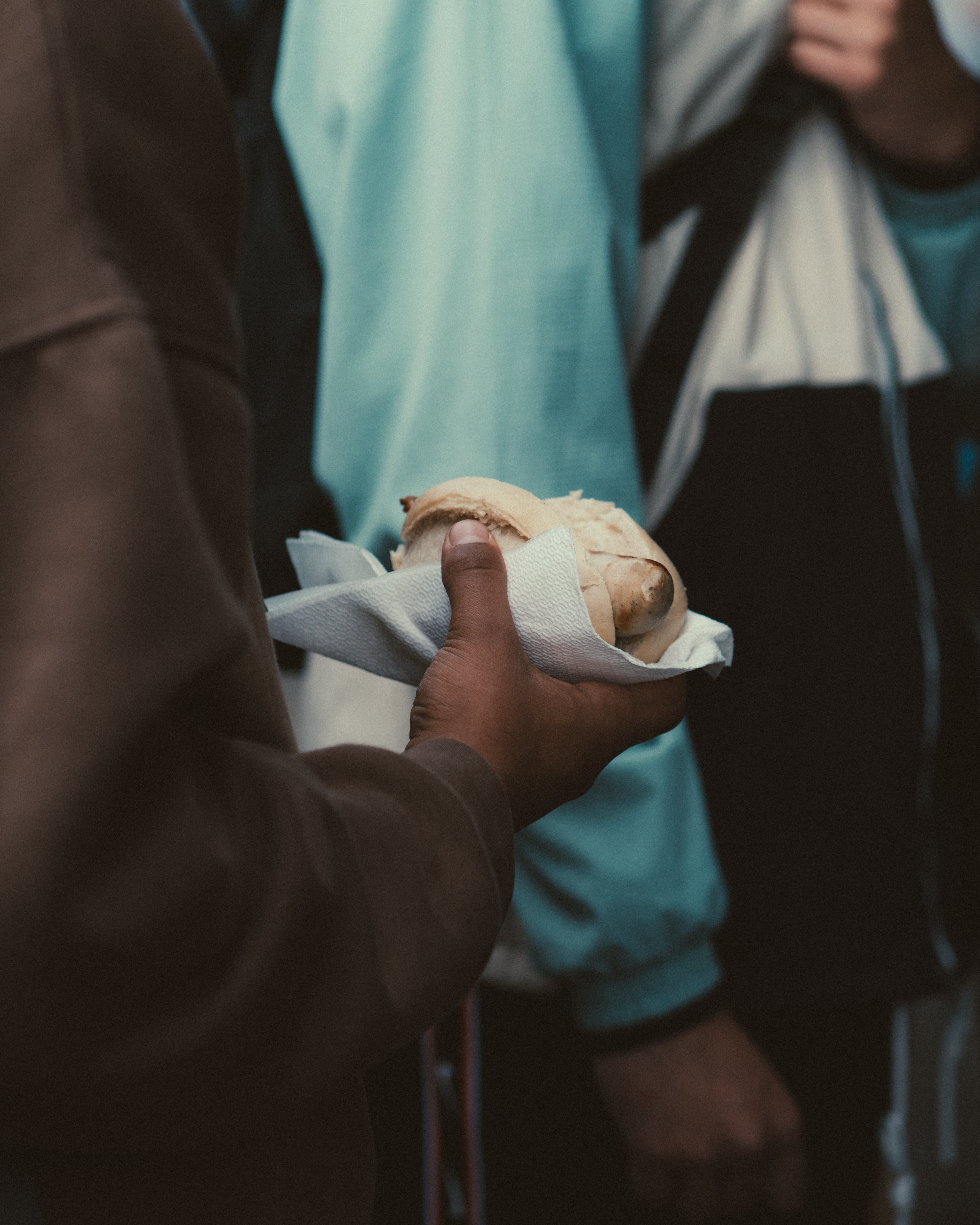A close-up shot of a man's hand holding a hot dog, highlighting casual, everyday dining moments.