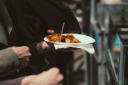 Person holding a plate of savory street food at an outdoor market.