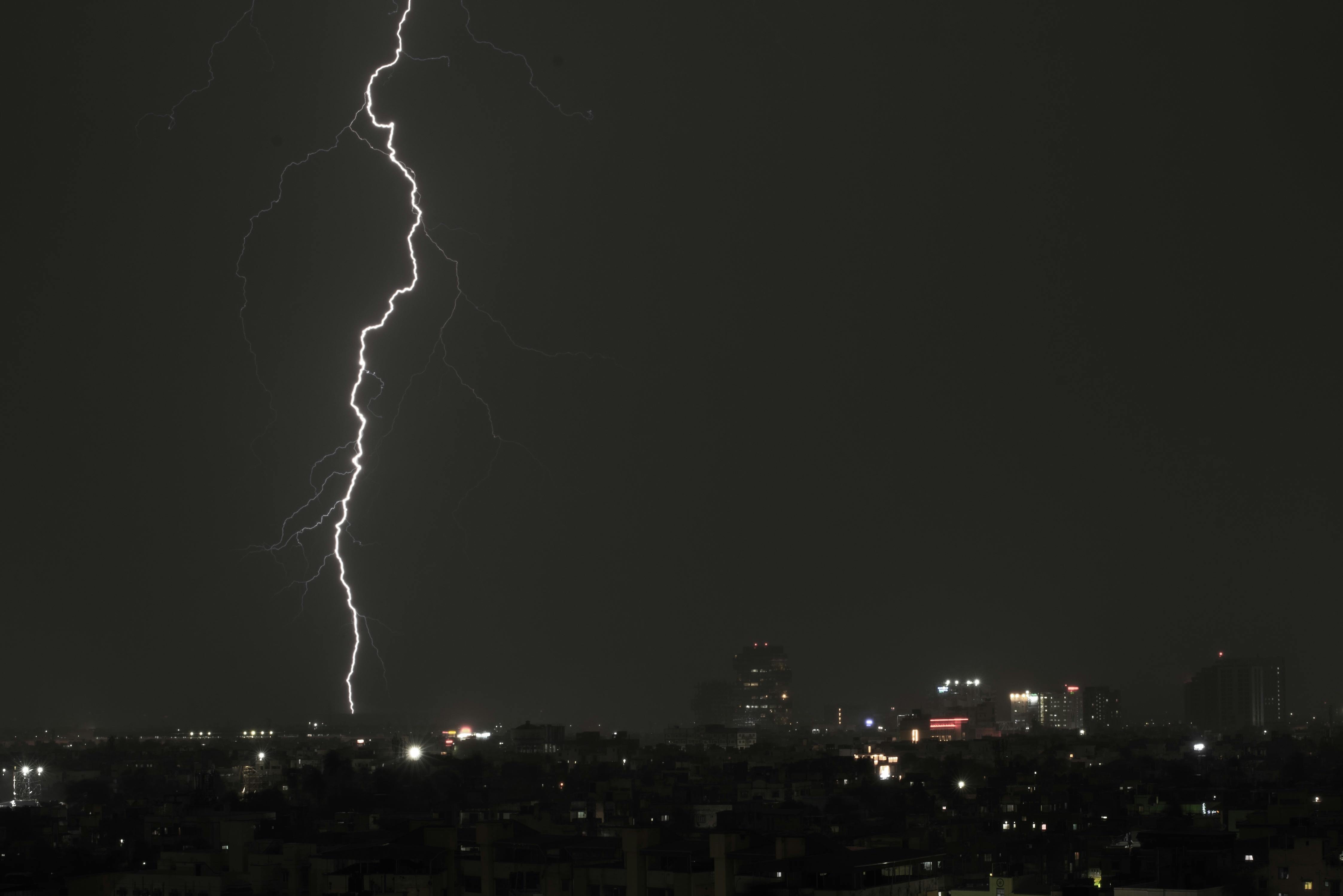Dramatic lightning bolt illuminates Kolkata's night sky over the urban cityscape.