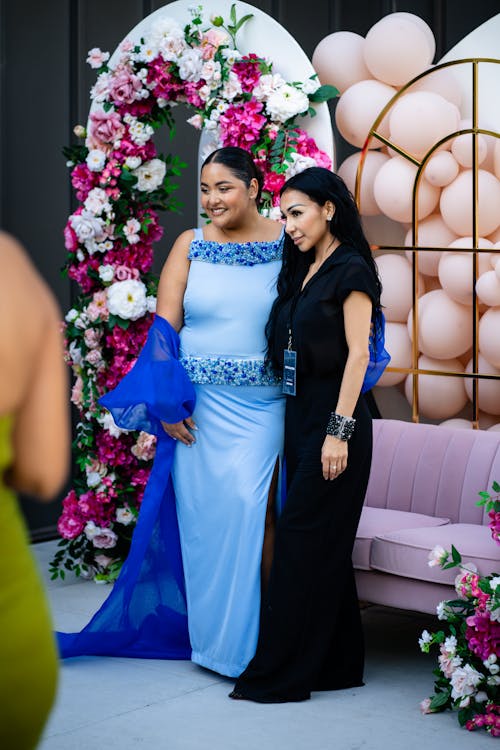 Two women in blue and black dresses standing next to each other