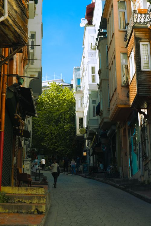 Free People walking in a sunny narrow alley lined with colorful residential buildings. Stock Photo