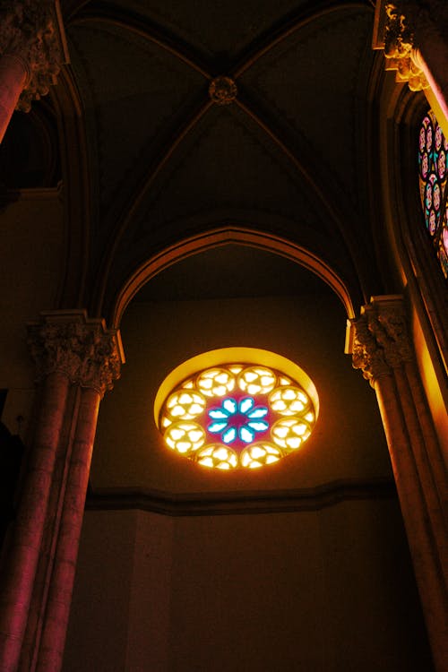 A stained glass window in a church with a light shining through it