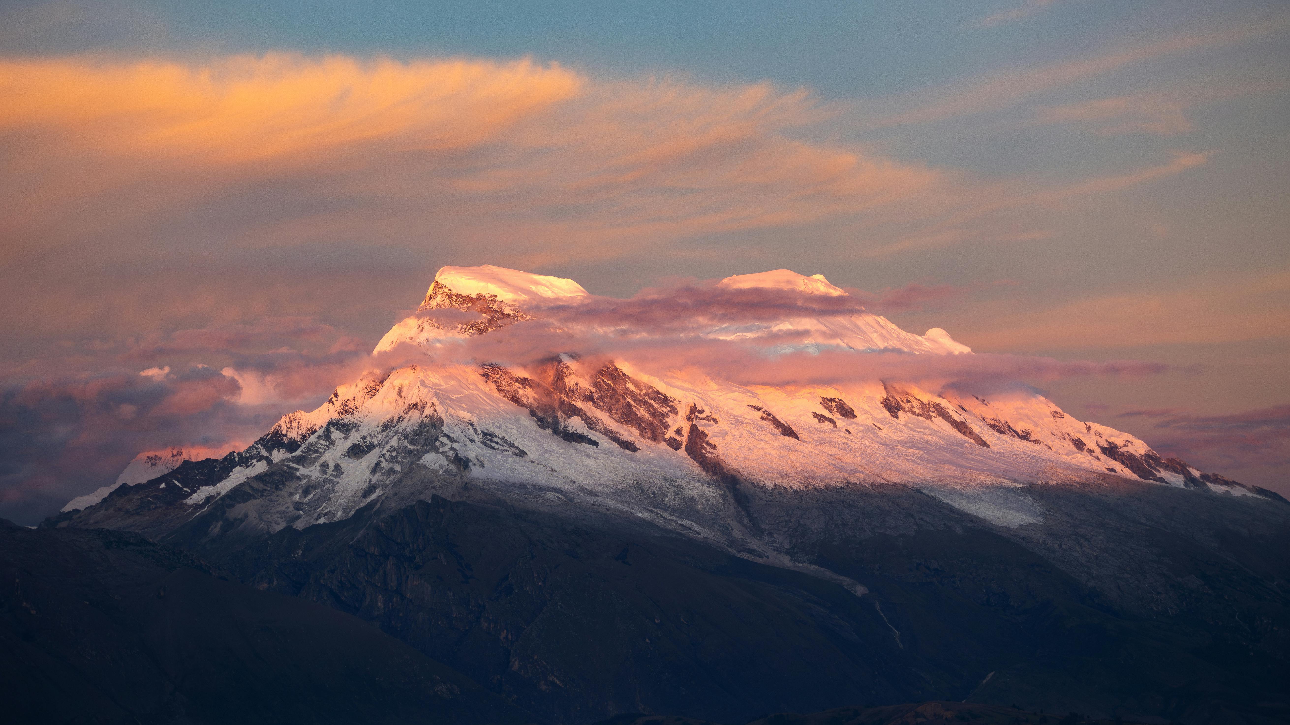 Breathtaking view of snow-covered peak at sunset in Huaraz, Peru, showcasing vibrant skies.