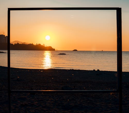 A picture frame on the beach with the sun setting