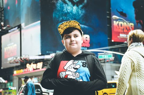 Free Young boy in a cartoon hoodie standing in Times Square, New York City. Stock Photo