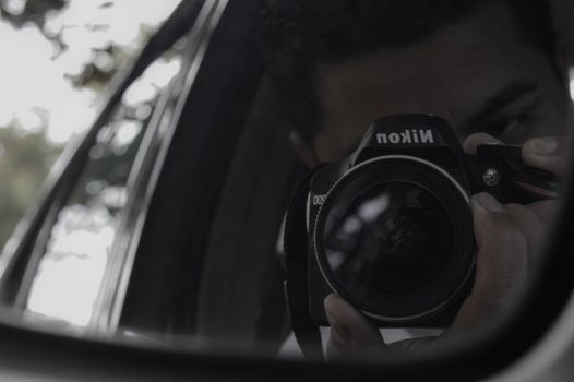 Reflection Of Man Holding Nikon Camera