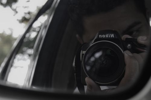 Free Reflective image of a photographer capturing with a camera in a car side mirror. Stock Photo
