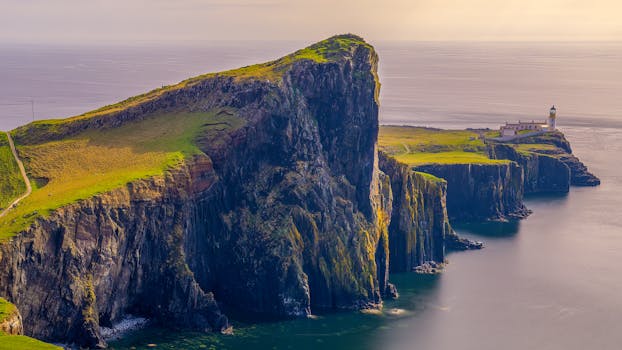 Stunning landscape of coastal cliffs with a distant lighthouse during daytime.