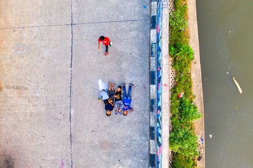 Free Bird's eye view of children playing on a concrete surface near an urban river. Stock Photo