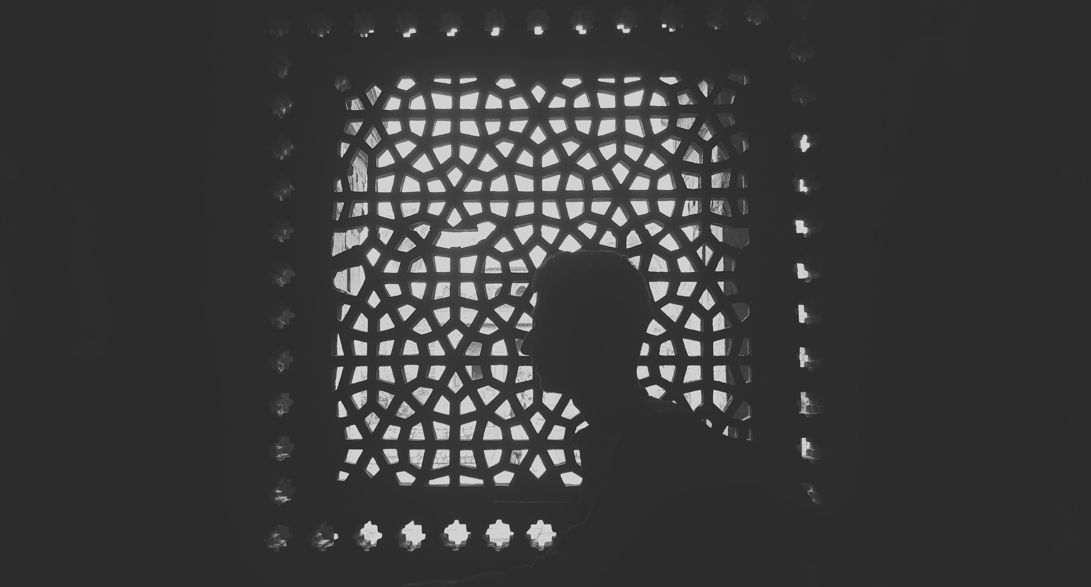 Free Dramatic silhouette of a man against a detailed lattice window in Delhi, India. Stock Photo