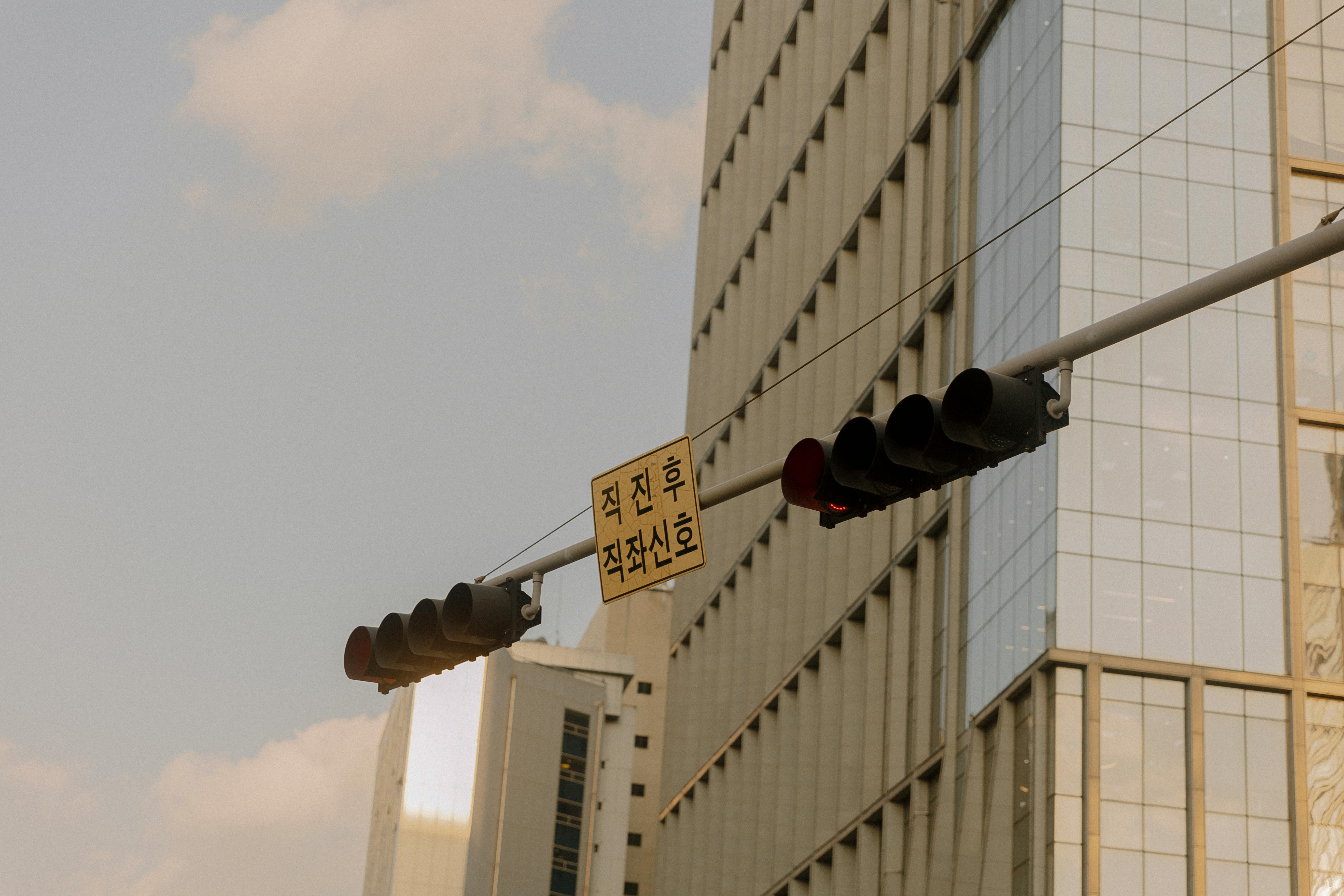 A traffic light and sign against the backdrop of a modern skyscraper in a city.