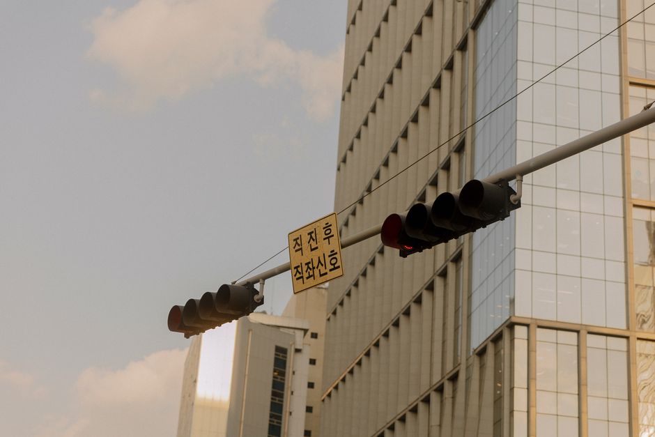 A traffic light and sign against the backdrop of a modern skyscraper in a city.