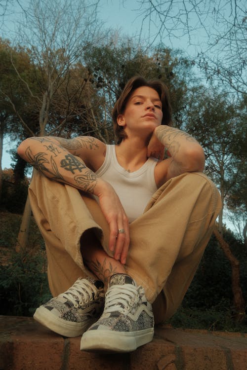 A woman with tattoos sitting on a brick wall