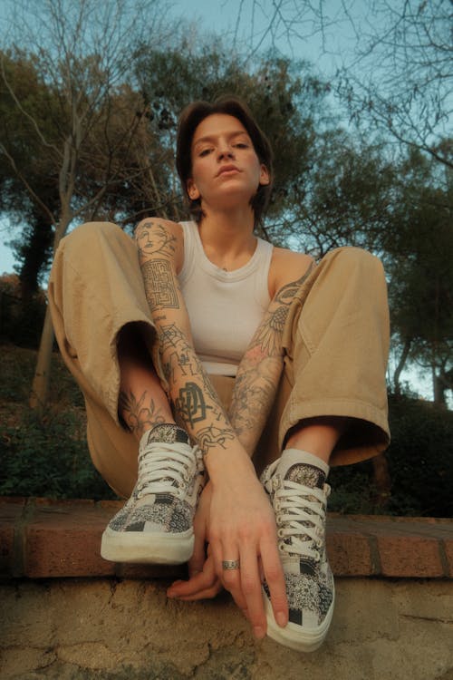 A woman with tattoos sitting on a wall