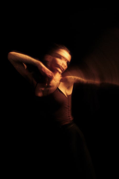 A woman in black is dancing in the dark
