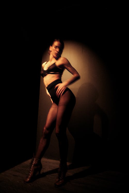 A woman in a black and white outfit posing in the dark