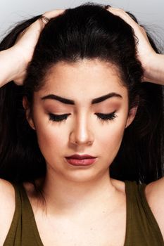 A studio portrait of a woman with stunning makeup and hair styling, eyes closed, showcasing beauty.