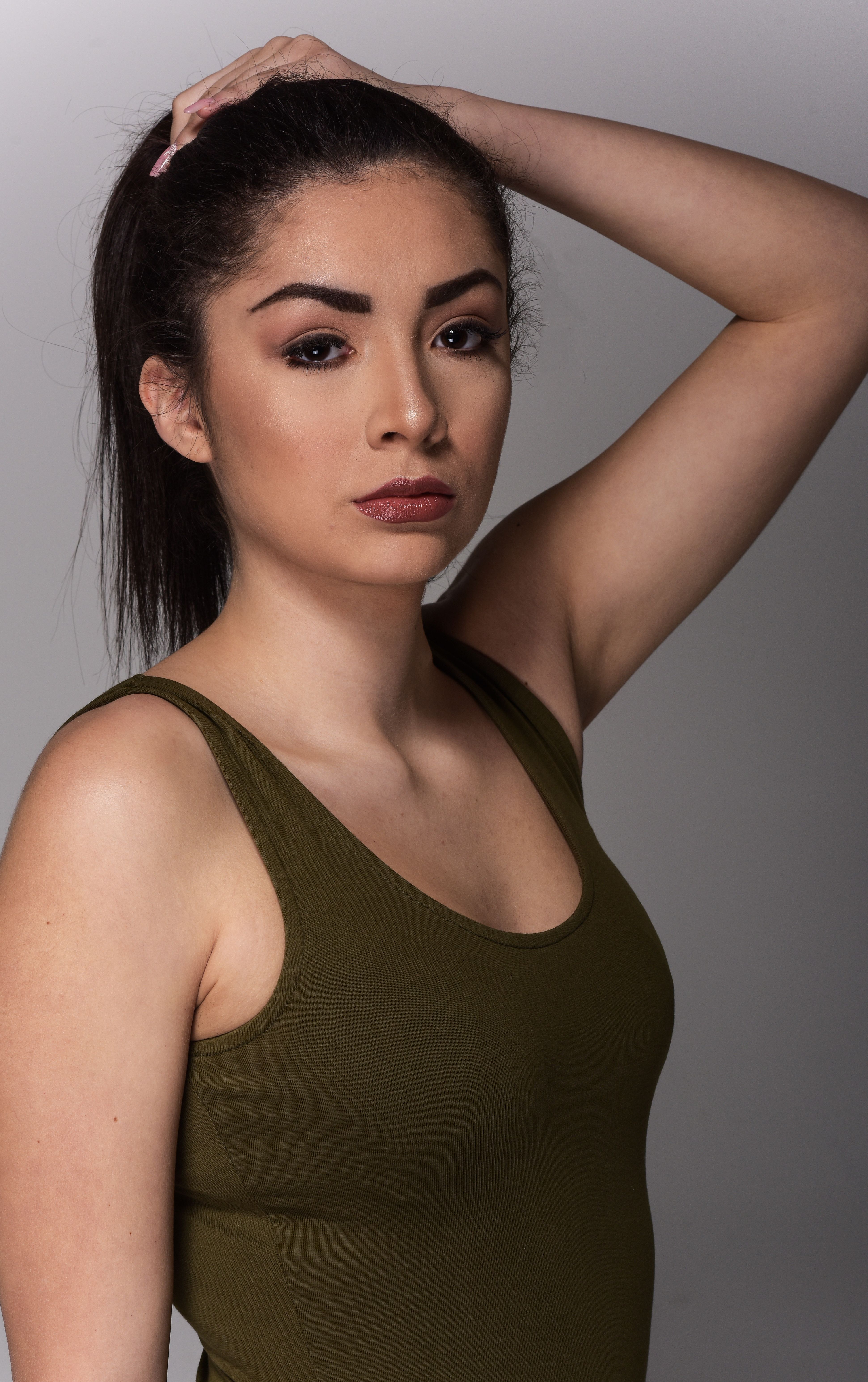 Young woman posing in a studio wearing a green tank top.