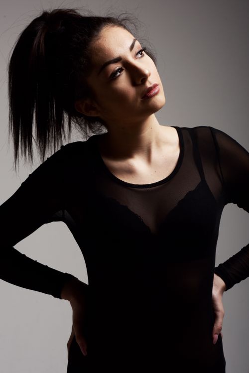 Free Portrait of a fashionable woman in a black sheer top posing in a studio setting. Stock Photo