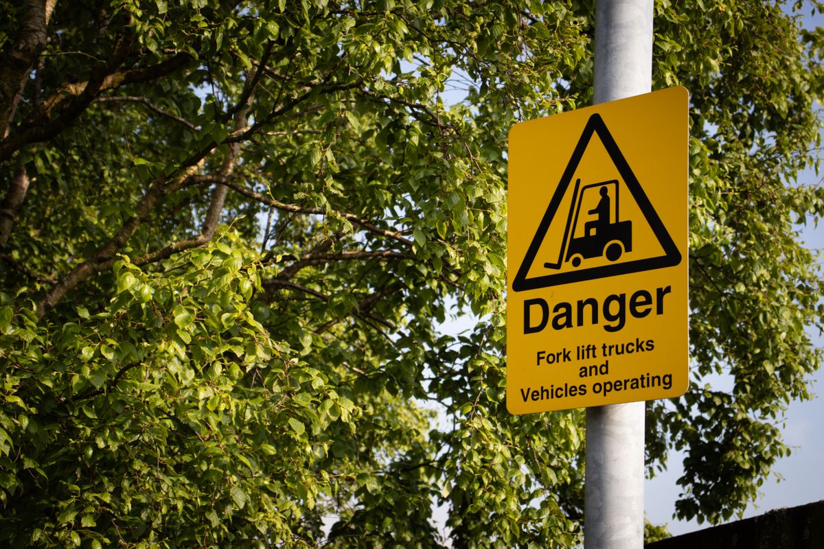 Yellow forklift warning sign on pole indicating vehicles operating in the area