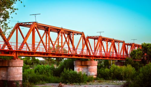 Free Vibrant red steel bridge spanning a lush green landscape in Pedro Meoqui, Mexico. Stock Photo