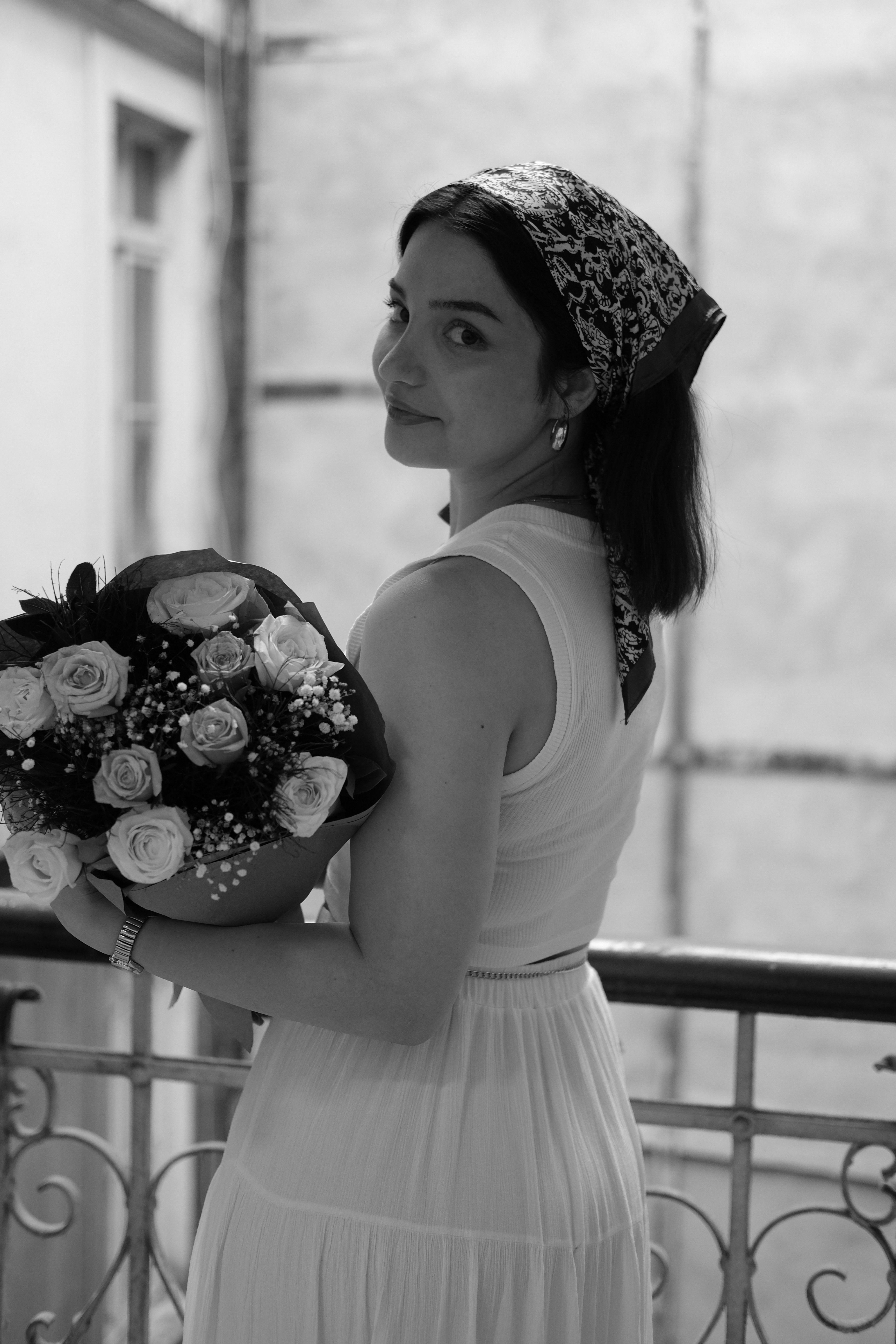 Black and white portrait of a woman holding a floral bouquet, capturing elegance and style.
