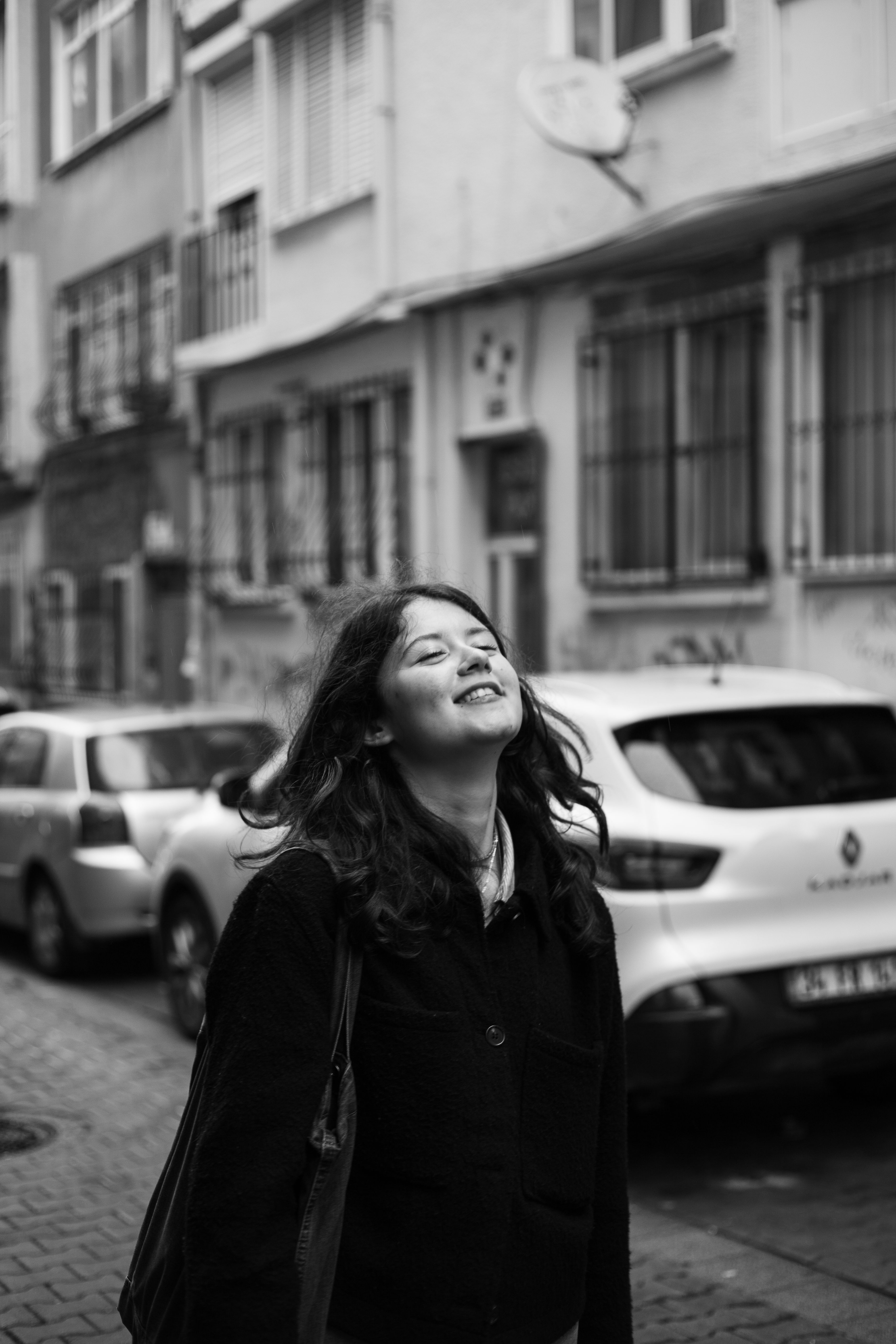 A woman smiles while walking through a city alley, capturing urban life.