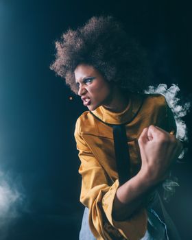 Motivated woman in yellow clothing striking a powerful pose in studio portrait.