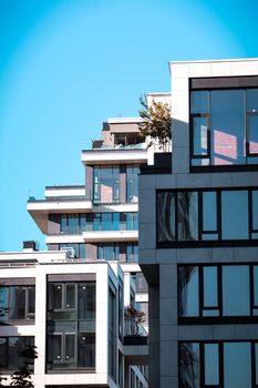 Sleek and modern urban apartment buildings with balconies and windows against a clear blue sky.