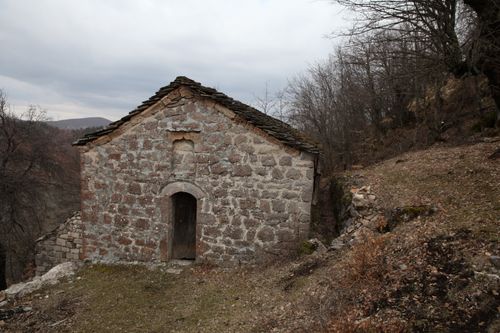Free Rustic stone building in Vithkuq, Albania, captures historic rural charm amidst wooded landscape. Stock Photo
