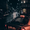 夜晚，雨水浸透的鹅卵石街道上，出租车穿行于戏剧性的城市街景中