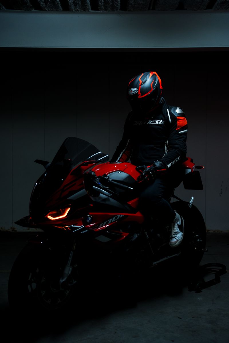 A motorcyclist in black and red gear sits on a sleek sportbike