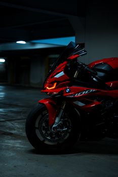 Close-up of a red sport motorcycle captured in a dimly lit garage, showcasing its sleek design.