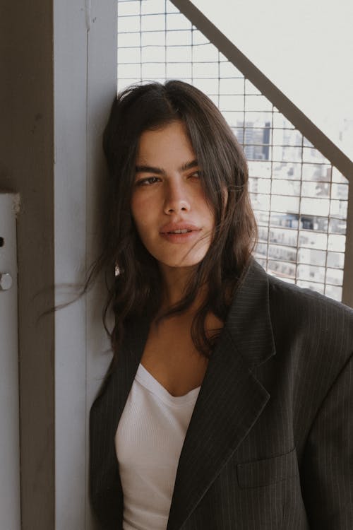 A woman leaning against a wall wearing a blazer
