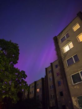 Aurora Borealis illuminates night sky above residential apartments in Vilnius, Lithuania.