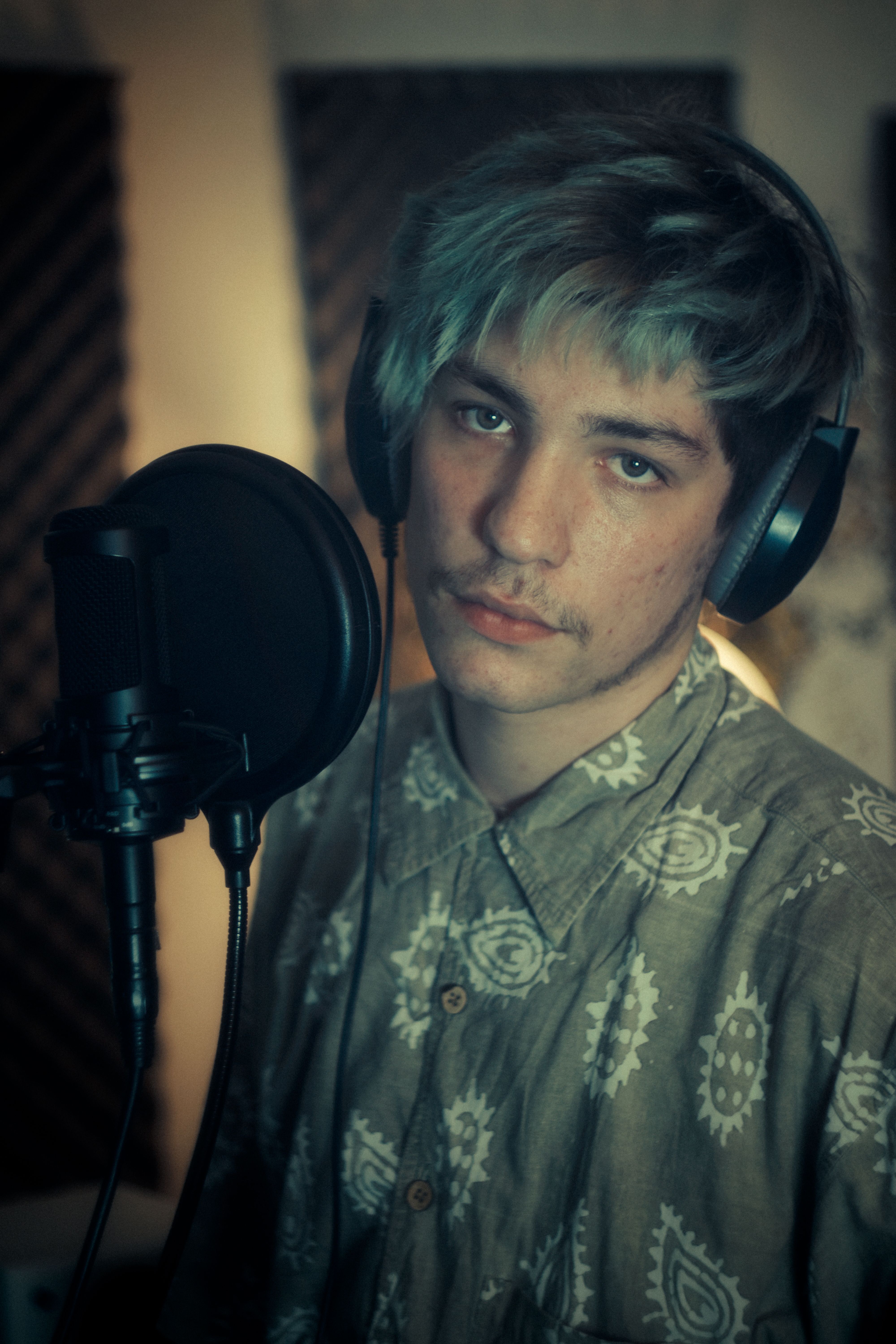Free A young musician with headphones at a microphone in a cozy studio setting. Stock Photo