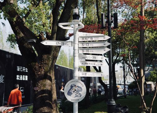 Free Multi-directional signpost in a Japanese park surrounded by lush trees and urban environment. Stock Photo