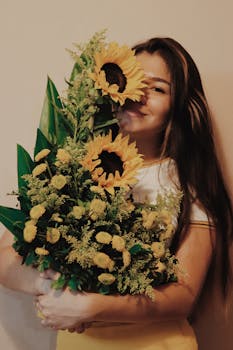 一位快乐的女士手持充满活力的向日葵，背景是中性的