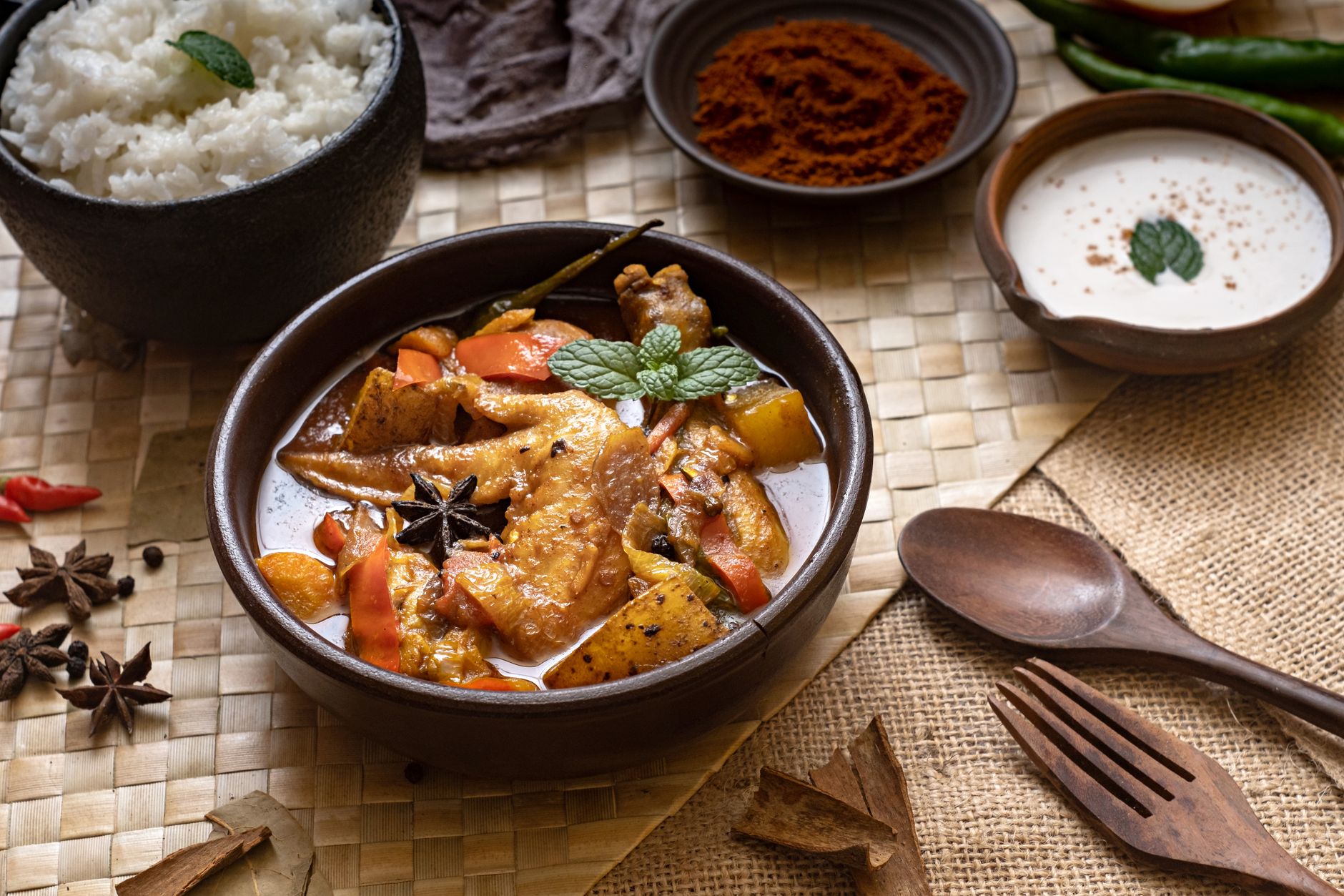 Steaming bowl of creamy Filipino pork stew with visible red chili peppers floating in rich coconut sauce, served alongside fluffy white rice