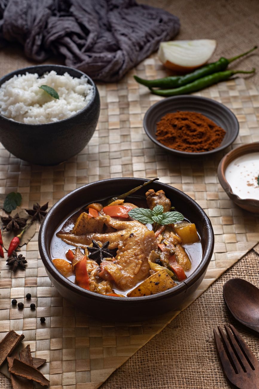 Golden Jamaican curry chicken with tender meat and potatoes in creamy coconut sauce, served in a bowl with white rice and fresh herb garnish