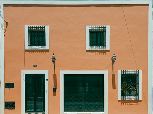 Free Vibrant orange facade of a house in Mérida, Mexico featuring decorative iron grilles on windows. Stock Photo