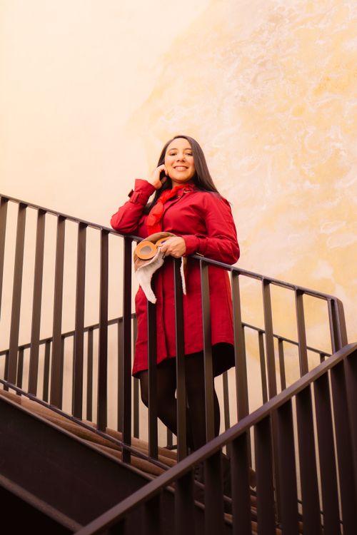 Free Smiling woman in red coat standing on stairs in Mexico City, showcasing urban fashion. Stock Photo
